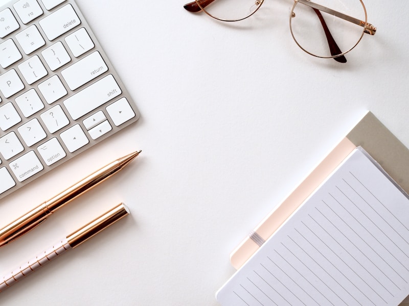 Pink notebook and pen with decorative items on light surface